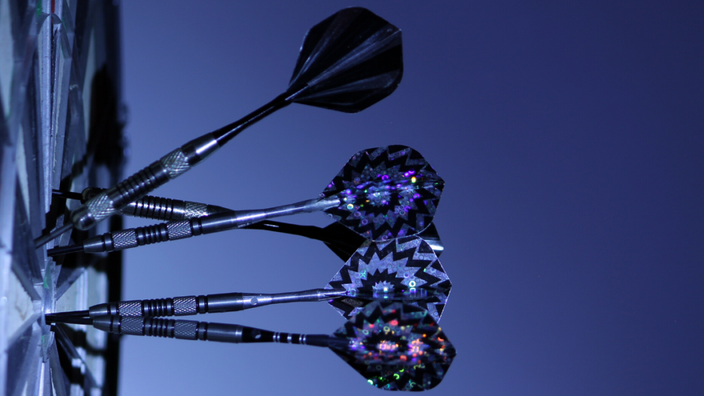 A picture of a dartboard with darts in it in an artistic blue light and from a side view. 