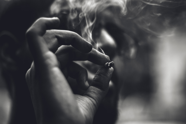 A black and white picture of a man smoking. His hand is in the forefront and you can just about see his head, but not his body. I chose it to represent addiction. 