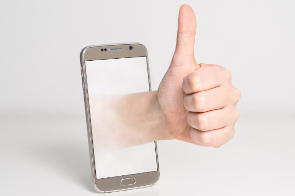 A picture of a hand with a thumbs up coming out of a mobile phone